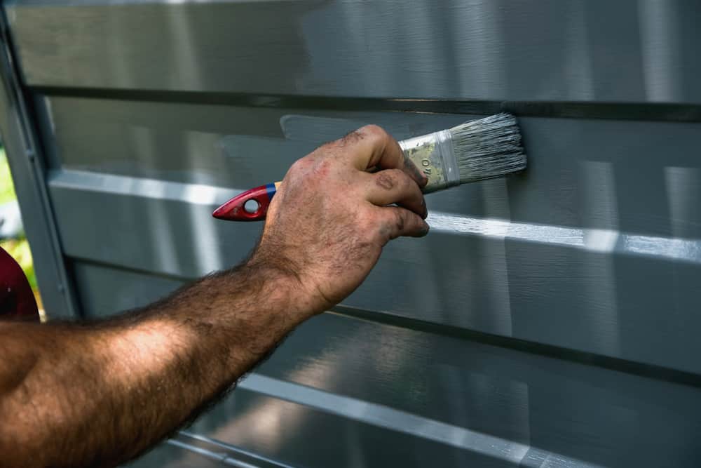A worker applying garage door coatings